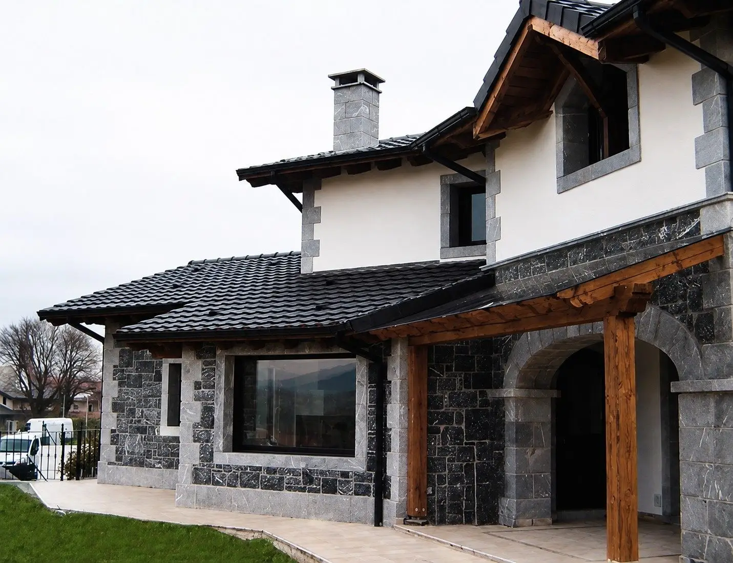 Vivienda unifamiliar en Berango con fachada de piedra caliza, mortero de cal y porche de madera