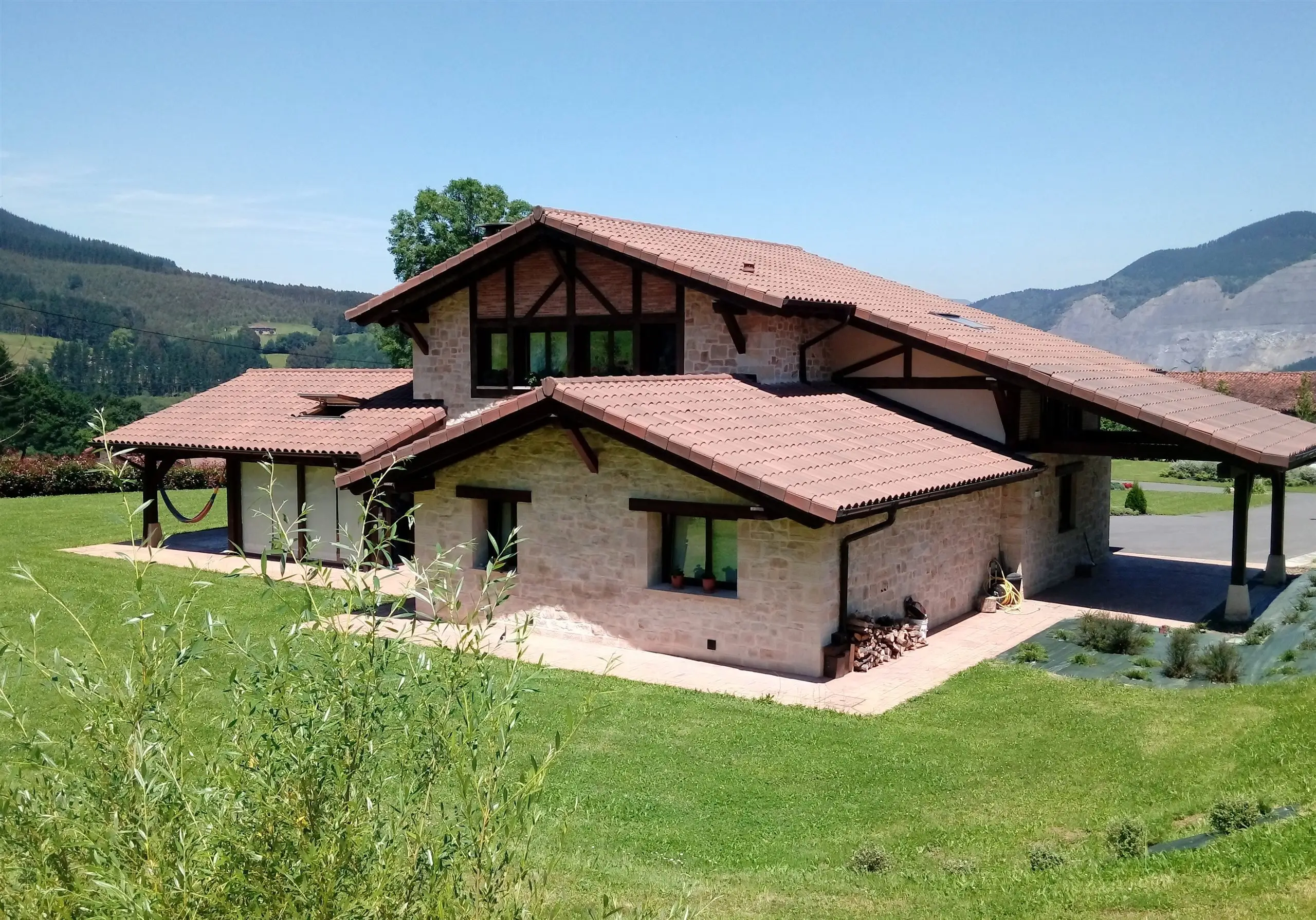 Vivienda unifamiliar en Garai (Orozko) con cubiertas de teja y fachadas de ladrillo, piedra y madera