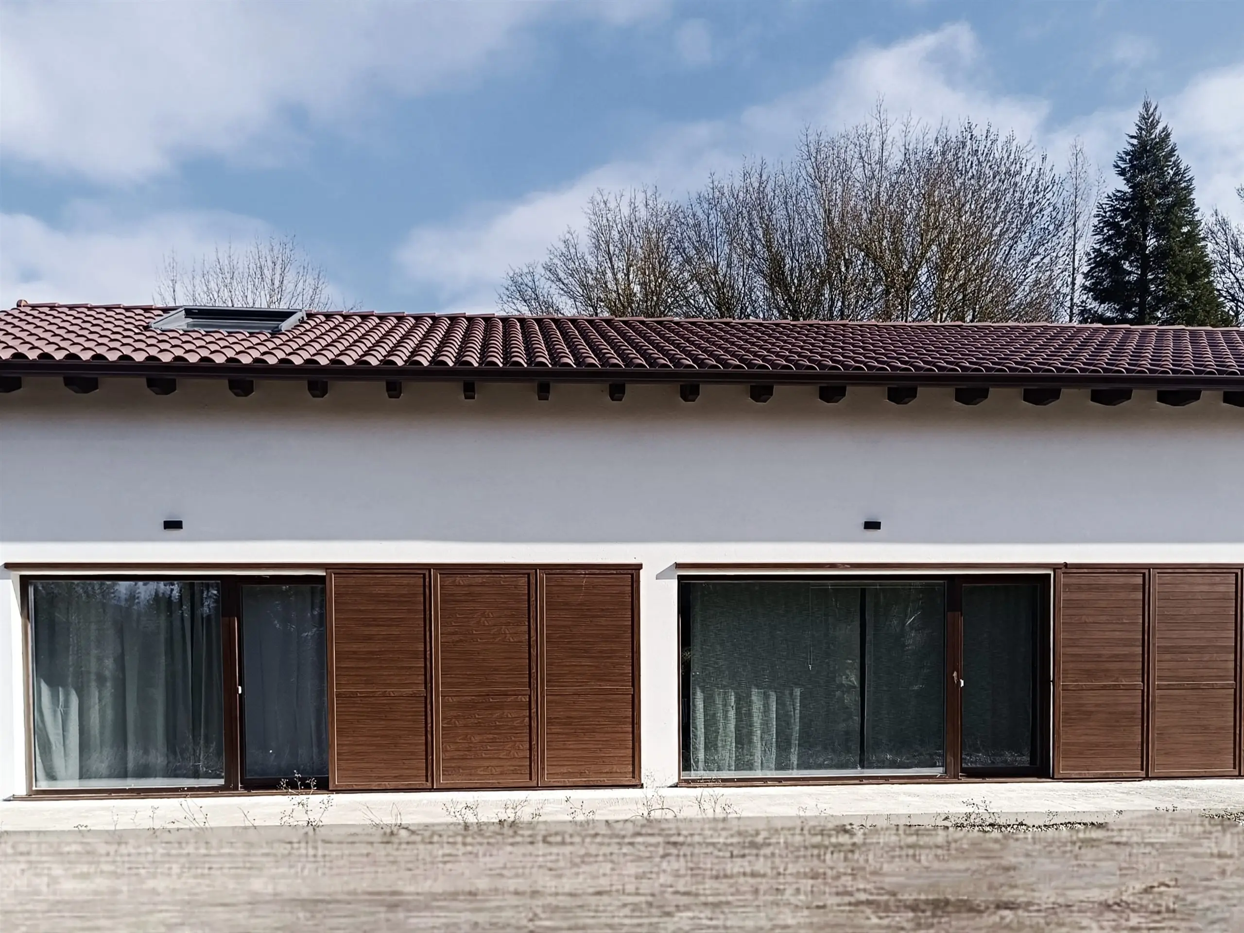 Fachada sur de la vivienda unifamiliar en Osacain con ventanales y contraventanas de madera
