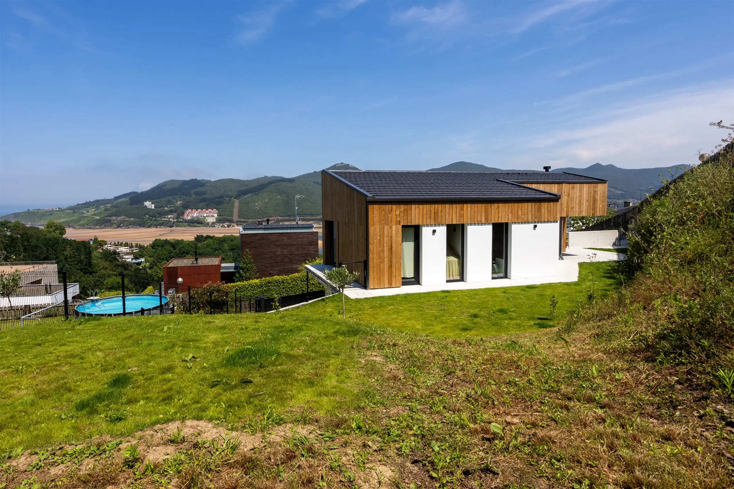 Vivienda unifamiliar en Sukarrieta sobre la ladera, con fachada de madera